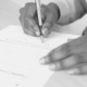 Black and White Photo of a man writing a contract