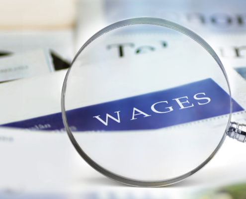 the word "wages" on a piece of paper zoomed in on with a magnifying glass